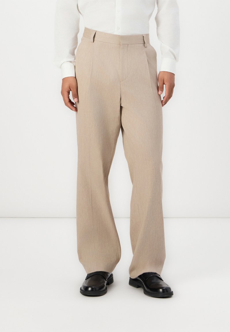 Pantaloni bej, cu croială ajustată și pantalon drept, dintr-un material texturat, cu plisuri frontale și talie plată.
