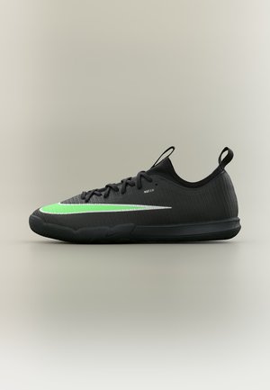 Chaussure de sport noire à coupe basse avec le logo Nike vert et blanc, lacets à l'avant et languettes à l'arrière du talon et sur la languette, conçue pour les sports en intérieur.