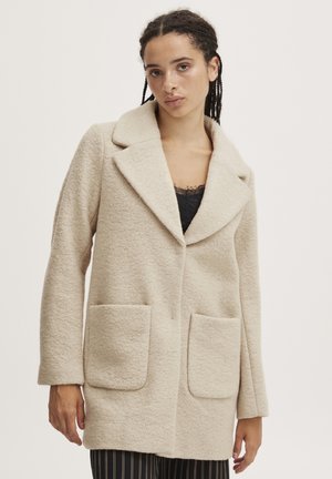 Manteau en mélange de laine beige avec un large revers, deux poches avant et des manches longues. Fini texturé avec une coupe décontractée.