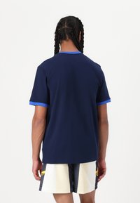 Mörkblå kortärmad t-shirt med rund halsringning, kontrasterande ljusblå ärmslut och en avslappnad passform. Tyget ser slätt ut.