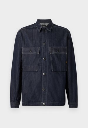 Dark blue denim jacket with long sleeves, collar, front button closure, and two large flap pockets with buttons on the chest.