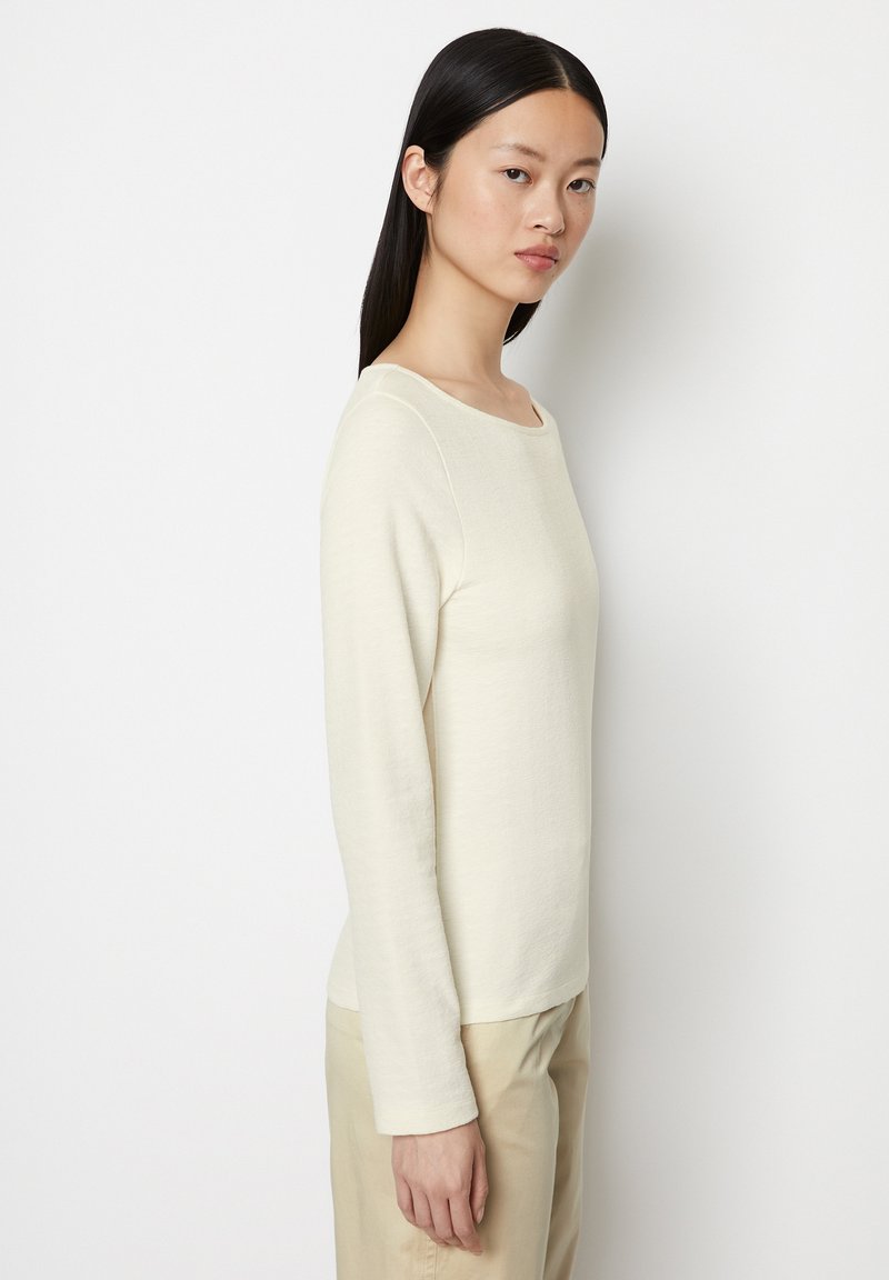 Crème lange mouw top met ronde halslijn, zachte textuur, aansluitend ontwerp en gladde naden, gecombineerd met beige broek.