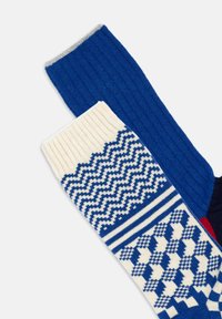 Calze rigate blu e crema. Una presenta un motivo a zigzag, mentre l'altra ha una parte superiore blu uniforme. Tessuto morbido a maglia, con texture a contrasto.