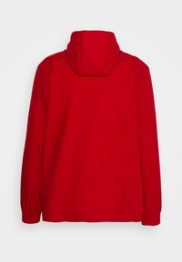 Giacca leggera rossa con cappuccio, polsini elasticizzati e una texture liscia. Nessun hardware o motivo visibile. Vista posteriore mostrata.