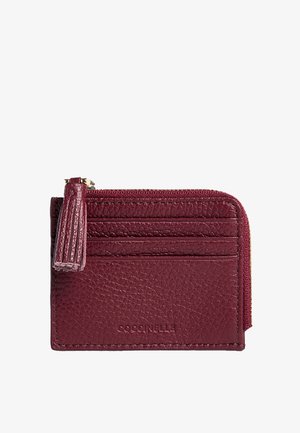Portefeuille compact en cuir bordeaux avec une poche zippée, trois fentes pour cartes et une finition texturée agrémentée d'un gland.