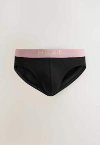 Sous-vêtements noirs de style slip avec une large ceinture rose portant le mot « NEXT » en lettres dorées, présentés sur un fond uni.