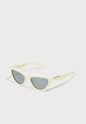 Ochelari de soare din plastic alb, forma ochi de pisică, cu lentile gri și accente metalice aurii pe temple. Textură netedă cu un design minimalist.