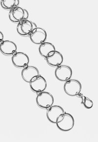 Srebrny metalowy łańcuch składający się z połączonych okrągłych ogniw, z zapięciem typu homar. Gładka faktura i błyszczące wykończenie.