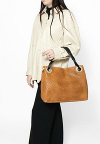 Borsa in pelle intrecciata di colore beige, con forma rettangolare, manici in pelle nera e dettagli in metallo argentato. La superficie presenta un motivo a tessitura a cestino.