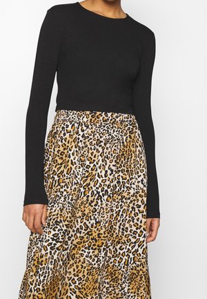 Haut noir à manches longues associé à une jupe imprimée léopard comportant des nuances de beige, noir et blanc, avec une taille élastique et une conception fluide.