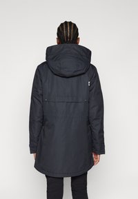 Zwarte geïsoleerde parka met een capuchon, featuring een gebogen zoom, ritssluitingen en een klein logo op de achterkant. Glad textuur, functioneel ontwerp.