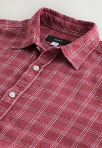 Rotes Flanellhemd mit weißem und blauem Karomuster. Mit spitzem Kragen, durchgeknöpfter Leiste und weißen Knöpfen. Markenlabel sichtbar.