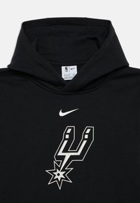 Hoodie nero realizzato in tessuto morbido. Presenta un logo Nike e una grafica stilizzata degli Spurs in bianco, centrata sul petto.