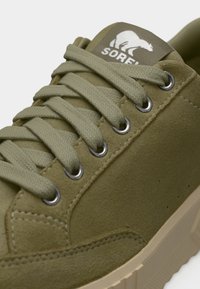 Λαδί πράσινο σουέντ αθλητικό παπούτσι με κορδόνια στο ίδιο χρώμα, ασημένιες οπές, μπεζ σόλα και ετικέτα στη γλώσσα με λογότυπο πολικής αρκούδας.