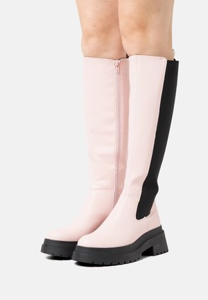 Støvler til knæhøjde i glinsende pink syntetisk materiale, sort stretchpanel, chunky sort sål og lynlås lukning på siden.