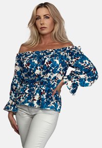 Bluzka z odsłoniętymi ramionami z białego materiału w niebieskie kwiatowe wzory, z falbaniastymi rękawami i marszczonym detalem w talii.