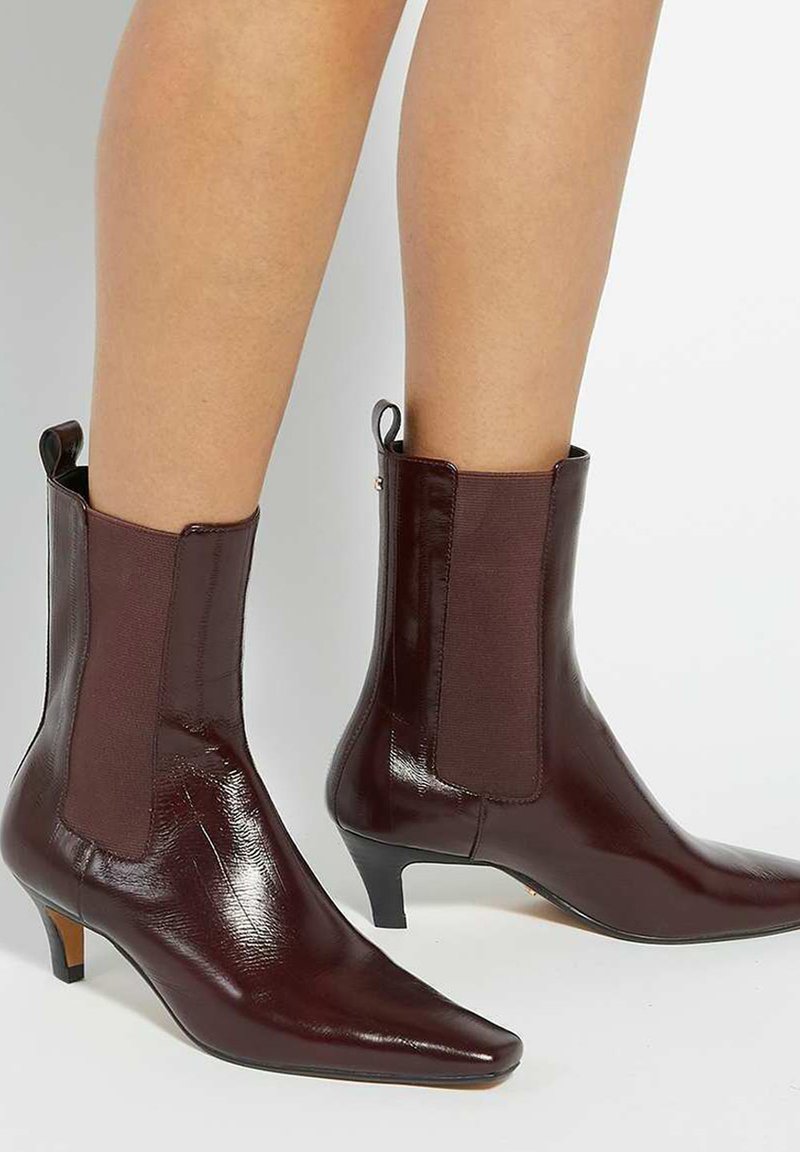 Burgundy ankle boots featuring a pointed toe and low heel with elastic side panels and a smooth, glossy finish.