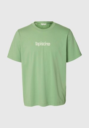 Lysegrøn T-shirt med korte ærmer og rund hals med den hvide tekst "lapiscine" trykt midt foran.