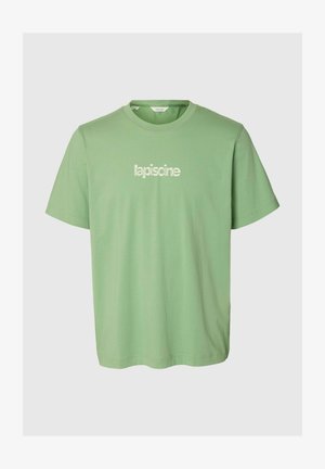 Lysegrøn T-shirt med korte ærmer og rund hals med den hvide tekst "lapiscine" trykt midt foran.