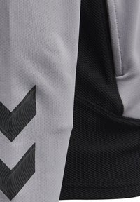 Tela atlética gris y negra con un patrón texturizado, que presenta gráficos en forma de chevron negros en la sección gris y un material liso en negro.