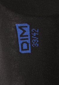 Schwarze Socken mit einem gewebten blauen Logo-Design. Die Textur wirkt glatt mit einem engmaschigen Muster. Keine sichtbaren Muster oder Akzente.