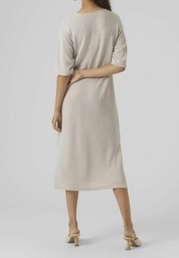 Vaaleanbeige ribbiknitti mekko, jossa on lyhyet hihat, keskik calf-pituus ja rento istuvuus. Yhdistetty beigenvärisiin korkoihin, joissa on paksu korkodeseeni.