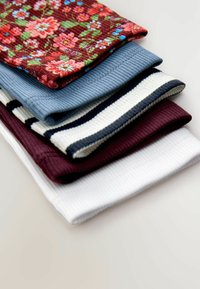 Stapel von gefalteter gerippter Stoffkleidung, darunter florale rote, hellblaue, weiß mit marineblauen Streifen, dunkelrote und schlichte weiße Teile.