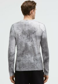 Langärmliges Shirt in Grau mit einem strukturierten, Farbspritzdesign. Hergestellt aus weichem Stoff, verfügt es über einen Rundhalsausschnitt und einen schlichten Schnitt.