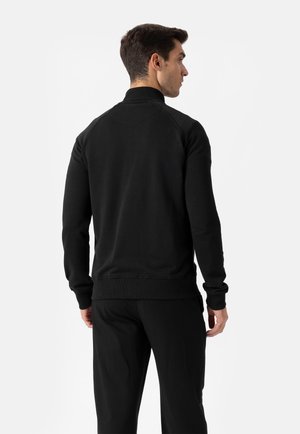 Črna jopa z visokim ovratnikom in raglán rokavi. Rebrasti manšeti in spodnji rob, izdelana iz mehke tkanine z gladkim teksturo.