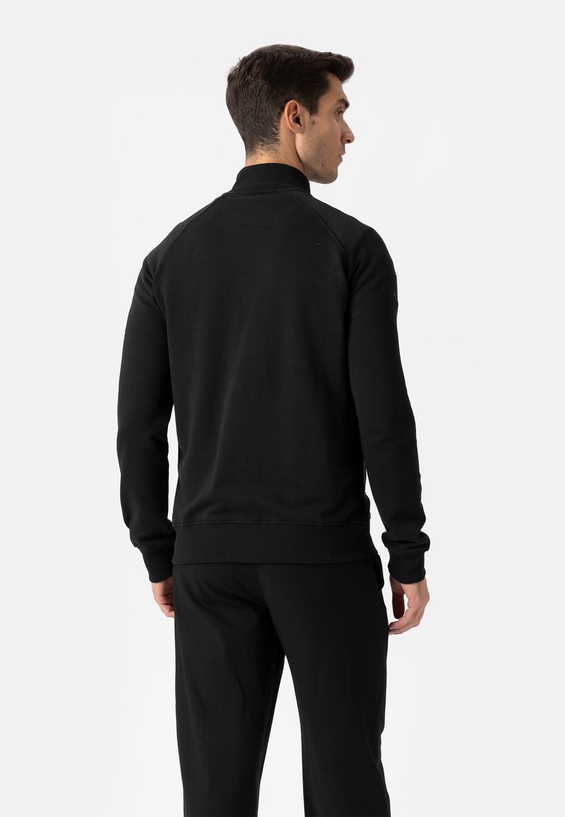 Mustad dressipluus kõrge kraega ja raglaanvarrukatega. Soonikkoes mansetid ja alaäär, valmistatud pehmest kangast, millel on sile tekstuur.