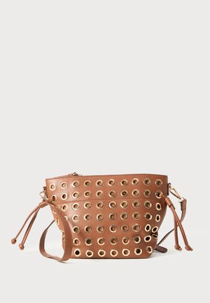 Bolso de cuero marrón con múltiples filas de ojales metálicos dorados y correa de hombro ajustable sobre un fondo blanco.