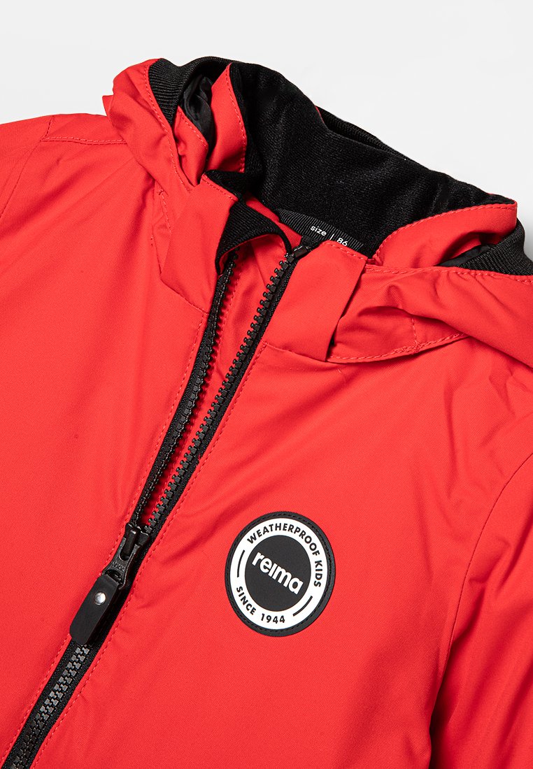 Rote wetterfeste Jacke mit schwarzem Reißverschluss und Kapuze, ausgestattet mit einem runden Logopatch, das "reima" und "wetterfeste Kinder" zeigt.