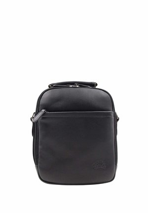 Sac d’épaule compact en cuir noir avec poche zippée à l’avant et poignée sur le dessus, logo embossé minimal en bas à droite.