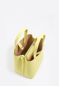 Żółta skórzana torebka z dwoma uchwytami, otwarta góra ukazująca wewnętrzną kieszeń na zamek i zapięcia na zatrzaski, beżowa podszewka wnętrza.