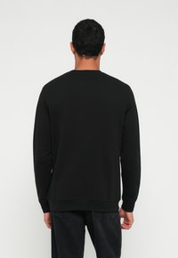 Felpa nera a maniche lunghe con scollo rotondo, realizzata in tessuto morbido, con polsini e orlo a costine e vestibilità comoda.