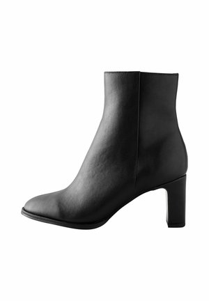 Bota de cuero negra hasta el tobillo con un diseño elegante, puntera cuadrada y un tacón ancho y resistente. Textura suave con líneas limpias y acentos mínimos.