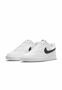 Baskets blanches avec un dessus texturé et des détails perforés. Logo Nike swoosh noir sur le côté. Semelle plate blanche au design minimal.