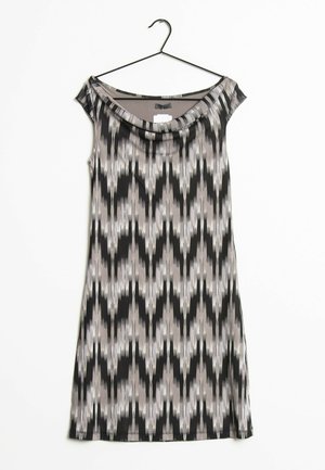 Robe sans manches avec un col drapé dans un motif géométrique noir, blanc et gris. Fabriquée à partir d'un tissu léger et lisse ; suspendue à un crochet noir.