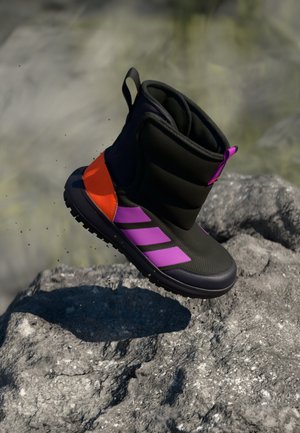 Botte noire avec des accents violets et orange, tige texturée, col rembourré et semelle en caoutchouc, conçue pour le confort et la traction.