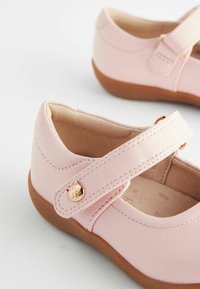 Roza usnjena Mary Jane čevlji z zaobljenim nosom, nastavljivim trakom in bakreno gumijasto zaponko v obliki mačke na strani. Rjava gumijasta podloga.