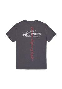 Šedé bavlněné tričko s nápisem "ALPHA INDUSTRIES" tučnými bílými písmeny a nápisem "Remove Before Flight" v červeném písmu na zadní straně.