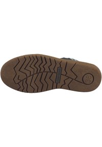Suela de goma marrón con patrón de tracción en zigzag y un detalle de logo circular. La etiqueta dice "joosebebel 38". Base plana para estabilidad y agarre.