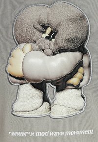 Prenda gris con una ilustración bordada de un personaje estilizado abrazándose a sí mismo. Los detalles incluyen tejido texturizado y acentos delineados.