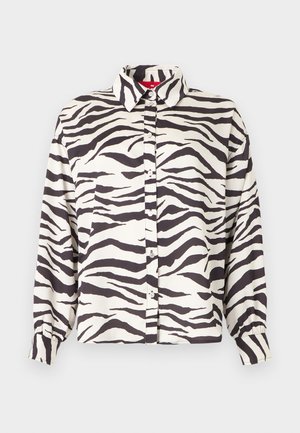 Marškiniai ilgomis rankovėmis su juodai baltais zebros dryžiais ir smailia apykakle ant šviesaus fono.