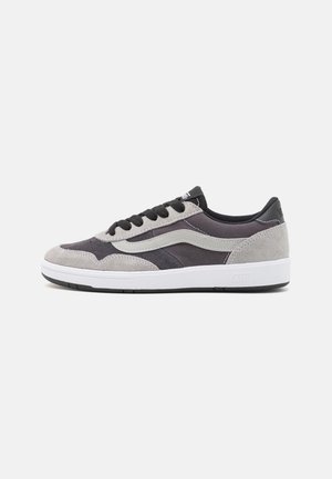 Zapatillas de gamuza y textil en gris y negro, con una suela de goma blanca, cordones negros y un destacado diseño de franja lateral.