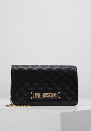 Czarna pikowana skórzana kopertówka Love Moschino z złotym łańcuszkiem i złotą plakietką z logo z przodu, umieszczona na białej powierzchni.