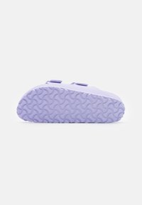 Purple rubber sandal with two adjustable straps, a textured sole featuring wavy patterns, and a smooth, curved upper design.