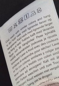Pračovný štítok s pokynmi na pranie symbolmi označujúci chladné pranie pri 40 °C, zákaz používania beľidla, sušenie v sušičke na nižšej teplote, žehlenie na nižšej teplote a zákaz čistenia suchou cestou.