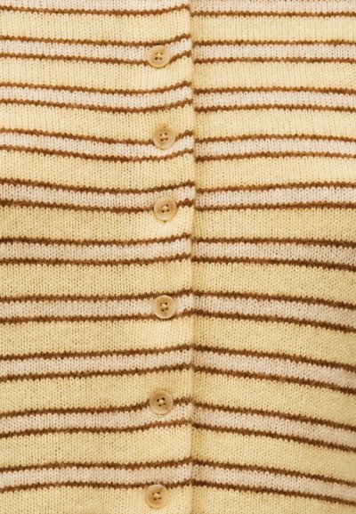 Μπεζ πλεκτό ύφασμα με οριζόντιες καφέ και κρεμ ρίγες, με μια κατακόρυφη σειρά από έξι μπεζ κουμπιά, το καθένα με τέσσερις τρύπες.
