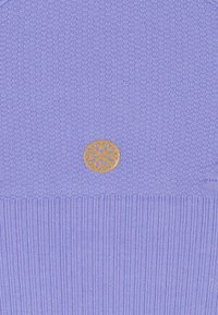 Lila gestricktes Kleidungsstück mit gerippter Textur am unteren Ende. Auf der Vorderseite befindet sich ein runder, goldener Emblem mit einem floralen Design.